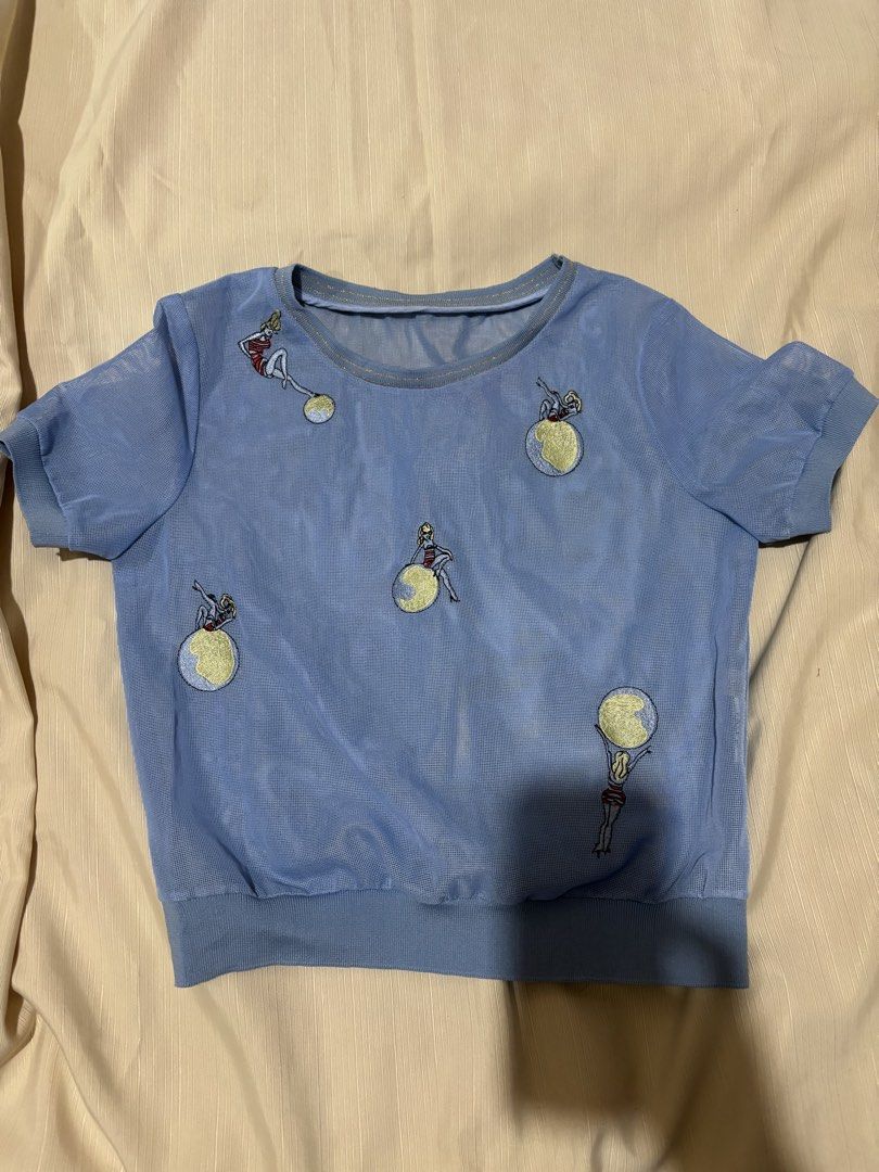 Blue Mesh Top with Embroidered Figures (Category: Sleeveless) located in Makati City. Submitted by issa124 (Listing ID 1464308833, Image 2). Description: - Light blue sheer mesh fabric - Short sleeves with ribbed hem and neckline - All-over embroidery featuring fun figures with yellow globes - Unique and eye-catching design - Perfect for layering or wearing as a standalone statement piece - chest - 15 inches .