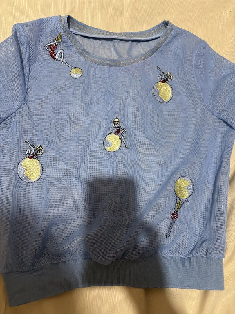 Blue Mesh Top with Embroidered Figures (Category: Sleeveless) located in Makati City. Submitted by issa124 (Listing ID 1464308833, Image 3). Description: - Light blue sheer mesh fabric - Short sleeves with ribbed hem and neckline - All-over embroidery featuring fun figures with yellow globes - Unique and eye-catching design - Perfect for layering or wearing as a standalone statement piece - chest - 15 inches .