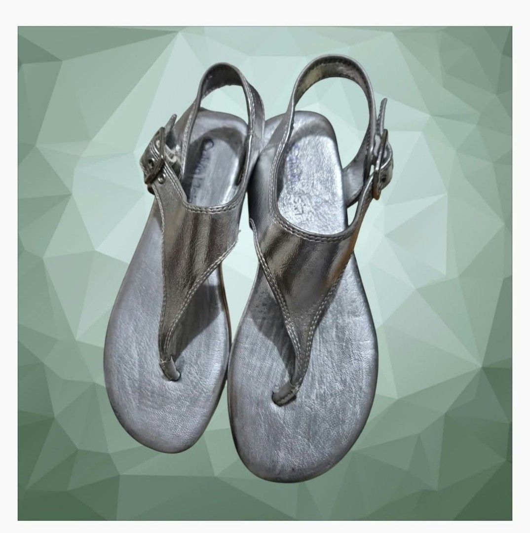 Calvin Klein Moraca T-Strap Flat Sandals (Category: Flats & Sandals) located in Paranaque City. Submitted by calm_youngstore7 (Listing ID 1464321616, Image 1). Description: Calvin Klein Moraca T-Strap Flat Sandals in a metallic silver colorway. Key Features • Design: Minimalist T-strap thong silhouette with a modern wide-set center panel. • Material: Crafted from a smooth, reflective metallic faux-leather upper with detailed perimeter stitching. 