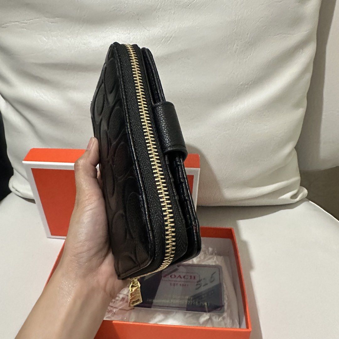 Coach Embossed Signature Wallet Black (Category: Wallets & Card holders) located in Marikina City. Submitted by bry_lei26 (Listing ID 1464181670, Image 2). Description: - Coach bi-fold wallet - Color: Black with all-over embossed signature C pattern - Hardware: Gold details - Closure: Snap closure with zip-around coin pocket - Interior: Card slots and clear ID window - Includes: Coach box - Origin: Made in Vietnam.