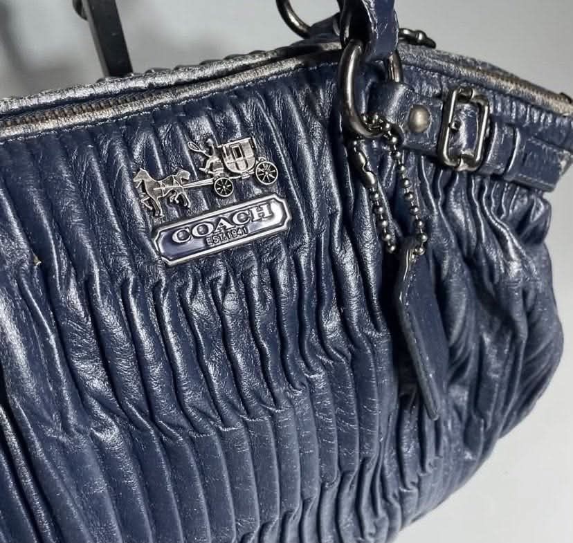 Coach Navy Blue Leather Ruched Shoulder Bag (Category: Luxury Bags & Wallets) located in Manila. Submitted by rufus_apparel (Listing ID 1464302583, Image 2). Description: - Navy blue Coach handbag - Made from soft, ruched leather - Silver hardware accents - Secure zipper closure - Interior fabric lining with serial number tag - Ideal everyday bag.