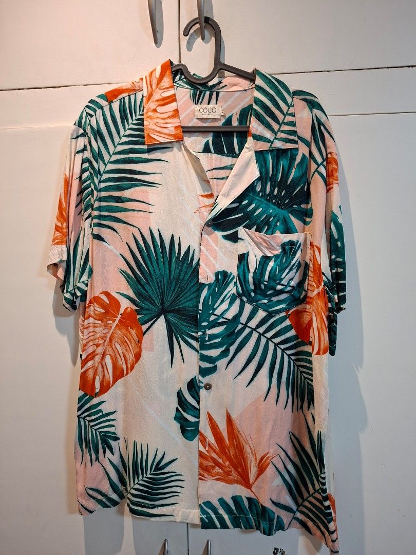 Coco Republic Tropical Leaf Print Button-Up Shirt (Category: Tshirts & Polo Shirts ) located in Paranaque City. Submitted by tabsi76 (Listing ID 1464264443, Image 1). Description: - Brand: Coco Republic - Style: Button-up shirt - Design: Tropical print with green leaves and orange accents - Background: Light pink and mint - Features: Chest pocket - Vibe: Casual, vacation - Size: XL - Selling for 250 pesos each.