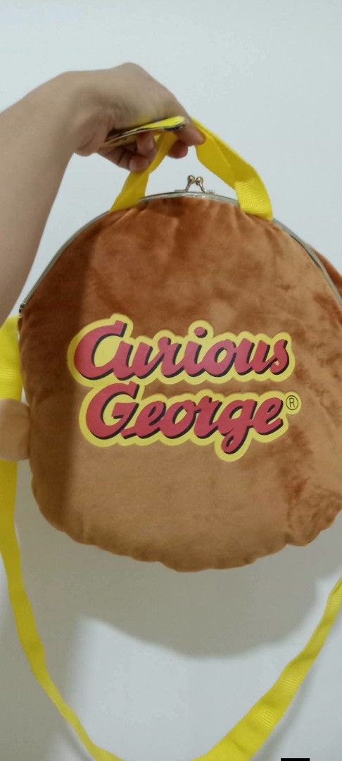 Curious George Plush Backpack Bag (Category: Plushies & Soft Toys) located in Gapan. Submitted by montesnora80204 (Listing ID 1464351218, Image 2). Description: - Adorable Curious George plush backpack - Features character's face on the front - "Curious George" name printed on the back - Lined with yellow satin inside - Secure clasp closure - Adjustable yellow straps - Ideal for children or Curious George enthusiasts.