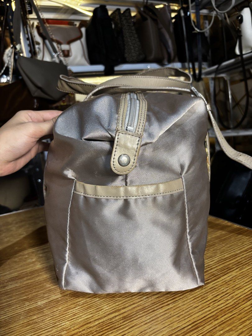 DAKS Silver Nylon Leather Trim Duffle Bag (Category: Luxury Bags & Wallets) located in Caloocan City. Submitted by _avionlineshop24 (Listing ID 1464138192, Image 2). Description: - Stylish silver duffle bag by DAKS - Accented with elegant tan leather trim - Iconic DAKS crest embroidered on the front - Secure zipper closure with a convenient leather pull tab - Practical side pockets for easy access - Ideal for weekend getaways or everyday adventur