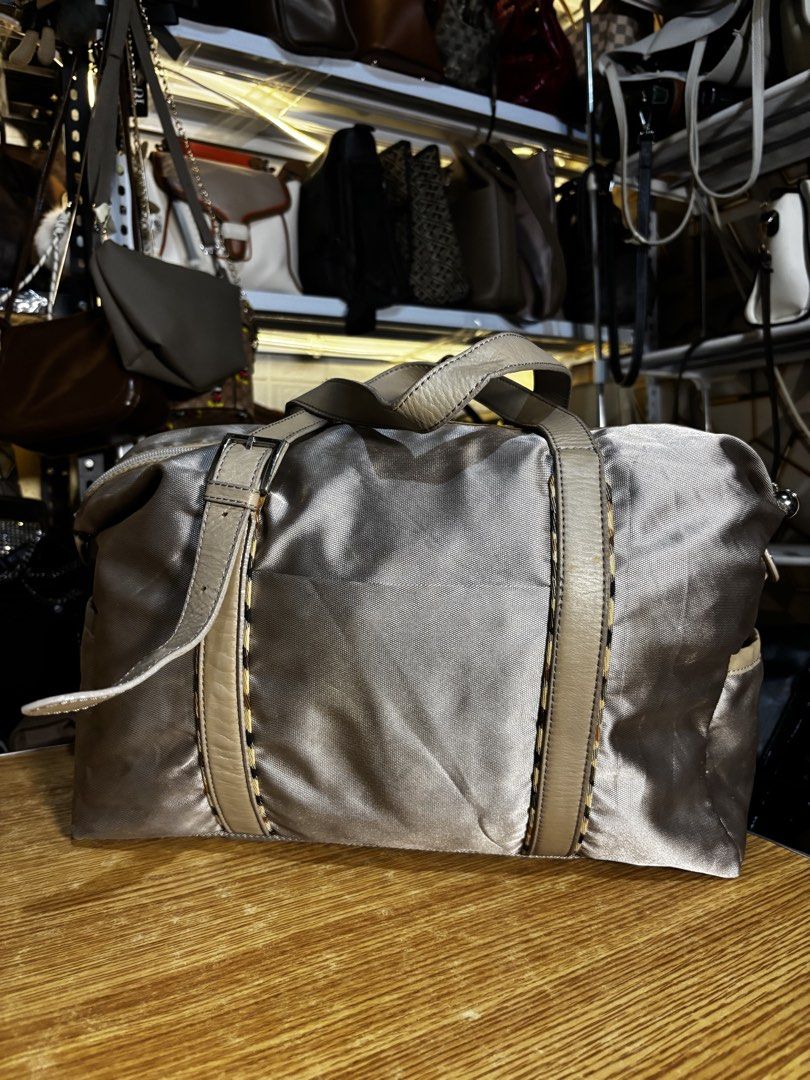 DAKS Silver Nylon Leather Trim Duffle Bag (Category: Luxury Bags & Wallets) located in Caloocan City. Submitted by _avionlineshop24 (Listing ID 1464138192, Image 3). Description: - Stylish silver duffle bag by DAKS - Accented with elegant tan leather trim - Iconic DAKS crest embroidered on the front - Secure zipper closure with a convenient leather pull tab - Practical side pockets for easy access - Ideal for weekend getaways or everyday adventur