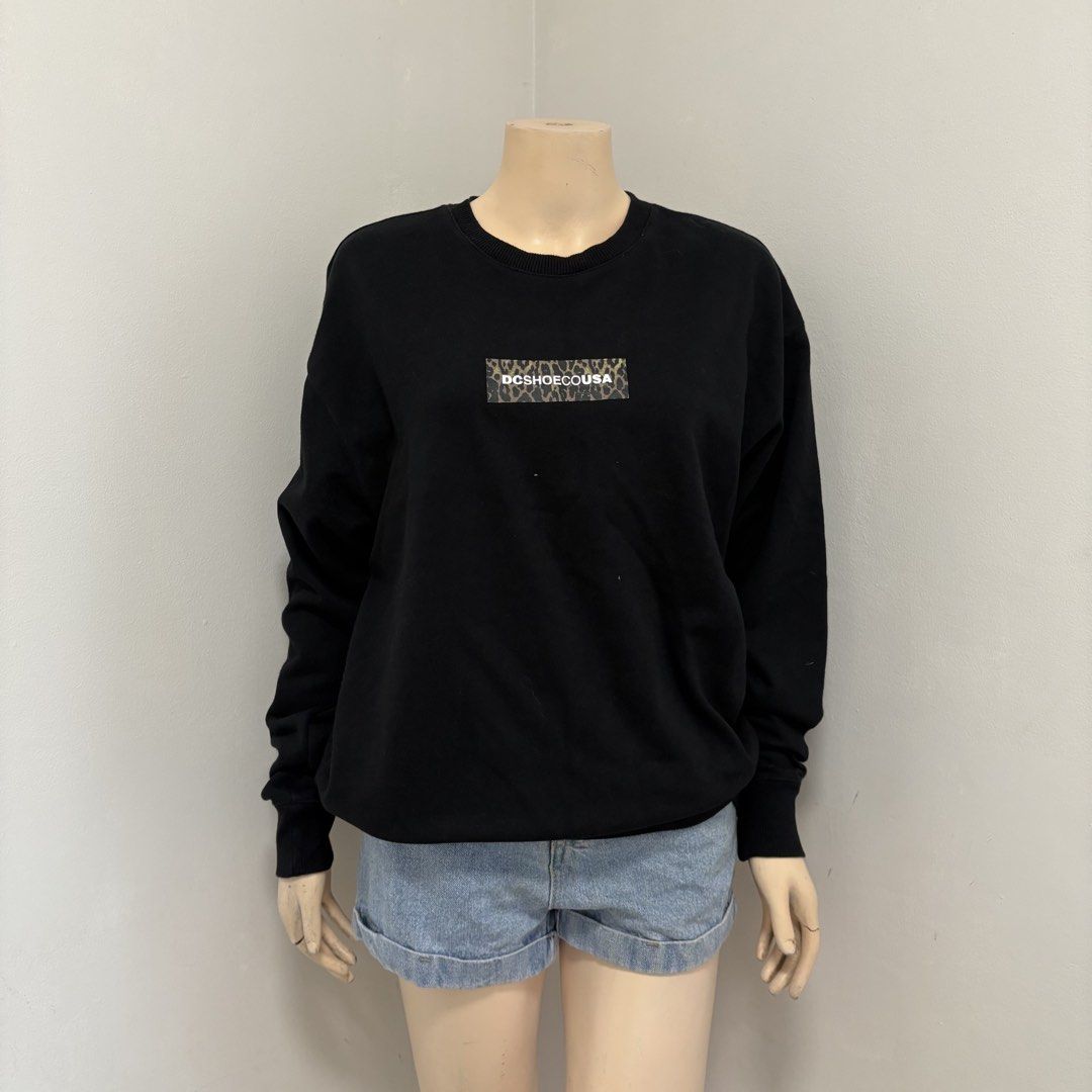 DC USA Black Crewneck Sweater (Category: Hoodies) located in Imus. Submitted by reloved.nd (Listing ID 1464244446, Image 1). Description: - Brand: DC Shoes USA - Type: Crewneck Sweatshirt - Color: Black - Design: Small rectangular chest logo with leopard print and white text - Features: Long sleeves, ribbed cuffs and hem - Style: Comfortable, casual, great for everyday wear.