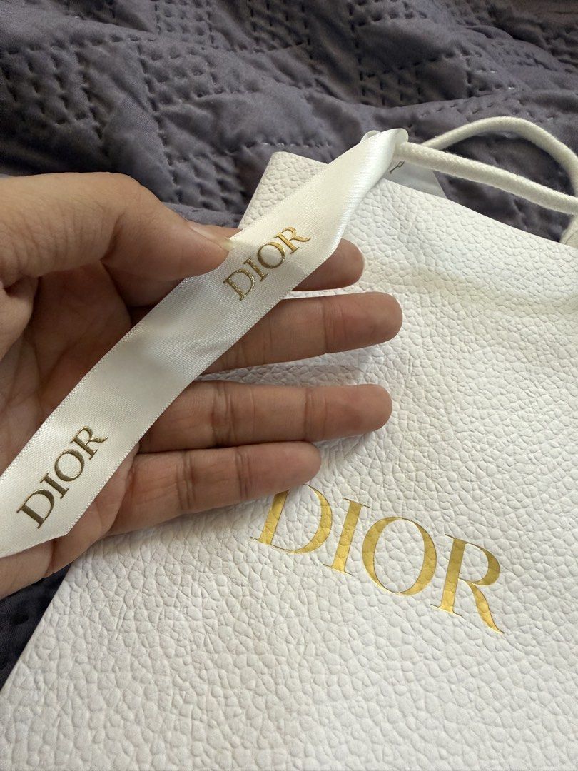 Dior White Textured Gift Bag with Ribbon (Category: Luxury Bags & Wallets) located in Quezon City. Submitted by ks_closet_cleaning (Listing ID 1464223677, Image 2). Description: - Authentic Dior gift bag - White textured paper with gold 'DIOR' logo - White satin ribbon with 'DIOR' print - Bee emblem inside the bag - Perfect for gifting or storing small items 2 pcs— 1 for lipstick and 1 for main bag .