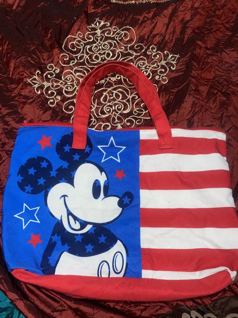 Disney Mickey Mouse American Flag Tote Bag (Category: Tote Bags) located in Manila. Submitted by reginemarquez412 (Listing ID 1464230974, Image 2). Description: - Adorable Mickey Mouse tote bag - Features a patriotic American flag design - Sturdy red handles for comfortable carrying - Secure zipper closure to keep your belongings safe - Includes an interior zippered pocket for small essentials - Spacious and versatile for everyday errands or trav