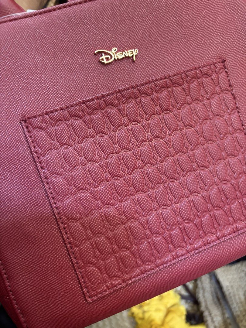 Disney Red Textured Tote Bag (Category: Tote Bags) located in Malabon City. Submitted by everythingpreloveddd (Listing ID 1464174764, Image 3). Description: - Cute red tote bag - Textured front pocket - Gold Disney logo - Zipper closure on the back - Mickey Mouse print lining inside - Snap button closure at the top - Great for everyday use.
