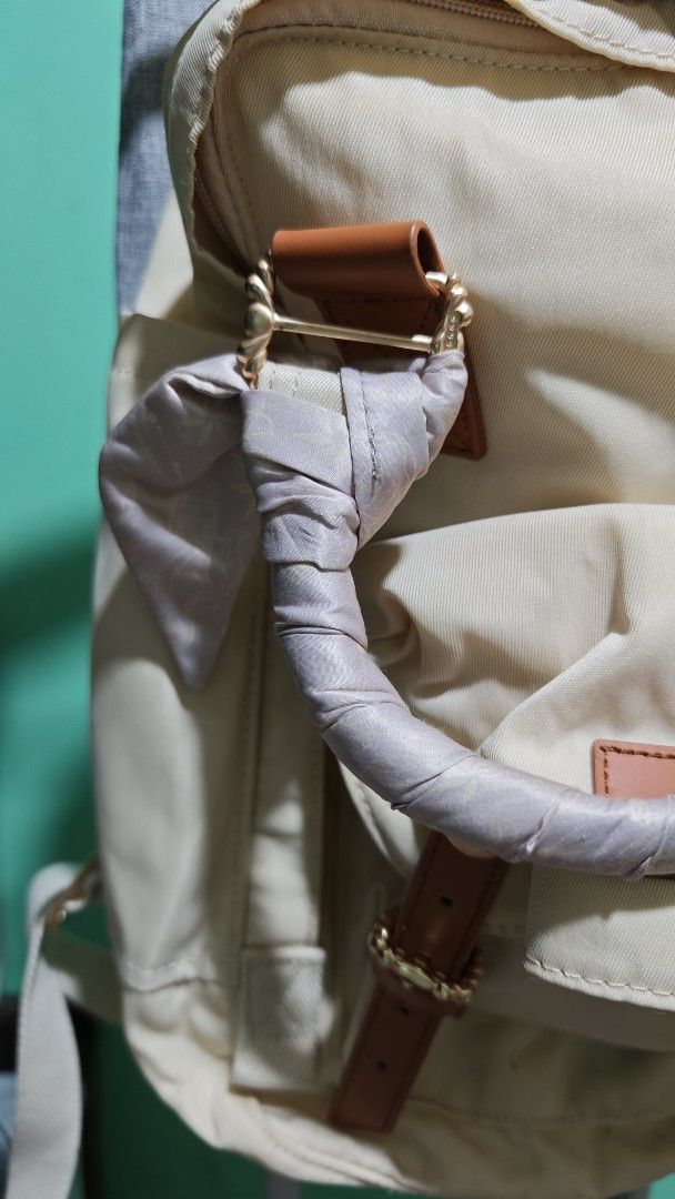 Doughnut Macaroon Grace Backpack Series (Category: Backpacks) located in Quezon City. Submitted by isabuys (Listing ID 1464193828, Image 3). Description: - Stylish beige backpack with elegant tan leather accents. - Adorable scarf tied around the handle for a unique touch. - Multiple pockets offer ample storage space. - Adjustable straps ensure a comfortable fit for all-day wear. - Ideal for everyday errands or your next travel adventure..