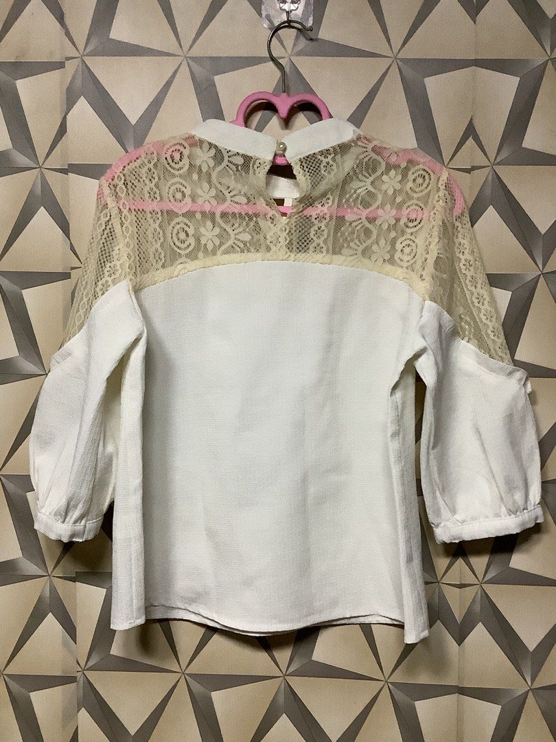 Elegant Lace-Panel Puff-Sleeve Blouse (Category: Blouses) located in Quezon City. Submitted by lovedbyerara (Listing ID 1464272314, Image 3). Description: Design Layout: It features a solid white opaque body panel juxtaposed with a sheer, floral-patterned lace yoke spanning across the upper chest, shoulders, and back. Neckline Detail: Designed with a mock-neck style collar, accented by a subtle teardrop keyhole cut-out at the center front. Sleeve