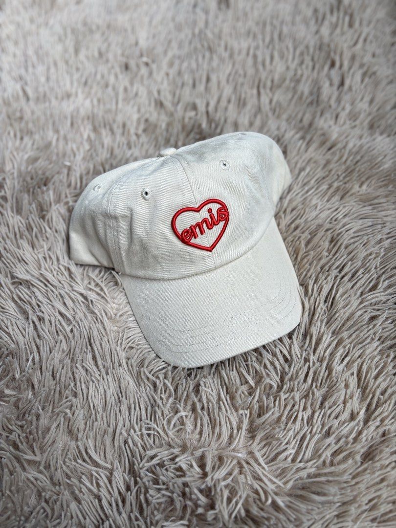 EMIS Heart Logo Baseball Cap Beige (Category: Caps & Hats) located in Quezon City. Submitted by nojthrift (Listing ID 1464252140, Image 1). Description: - Brand: EMIS - Color: Beige - Design: Classic baseball cap - Features: Embroidered red heart logo on front - Fit: Adjustable strap at the back - Style: Perfect for everyday wear.