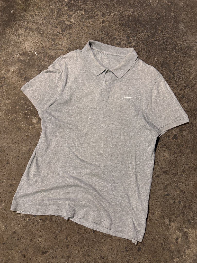 Grey Nike Polo Shirt (Category: Tshirts & Polo Shirts ) located in Pasig City. Submitted by dripthrift1600 (Listing ID 1464248947, Image 1). Description: - Grey Nike polo shirt - Short sleeves with collar and button placket - Features a small Nike swoosh logo on the chest - Versatile for casual wear or sports activities - **Condition Note:** Has a small hole on the back, as shown in the last photo. - Dimes: 21x28.