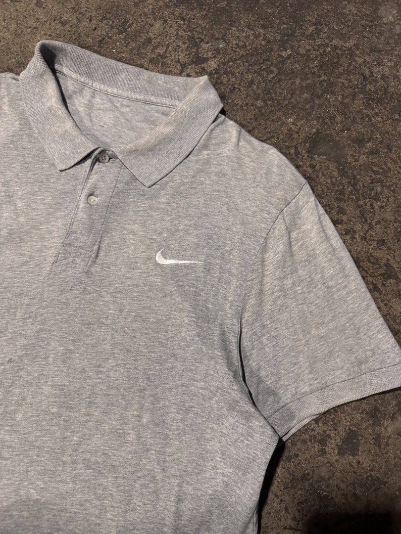 Grey Nike Polo Shirt (Category: Tshirts & Polo Shirts ) located in Pasig City. Submitted by dripthrift1600 (Listing ID 1464248947, Image 3). Description: - Grey Nike polo shirt - Short sleeves with collar and button placket - Features a small Nike swoosh logo on the chest - Versatile for casual wear or sports activities - **Condition Note:** Has a small hole on the back, as shown in the last photo. - Dimes: 21x28.