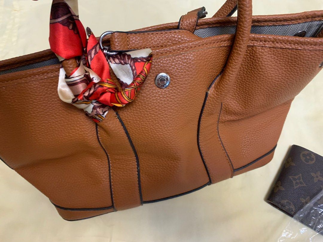 Hermes Brown Leather Handbag with Scarf Accent (Category: Shoulder Bags) located in Bulacan. Submitted by heartlove_holb (Listing ID 1464298621, Image 1). Description: - Genuine brown pebbled leather handbag - Adorned with a decorative scarf tied to the handle - Top zipper closure for security - Interior includes a zippered pocket and a slip pocket - Slip pocket features 'Hermes Paris Made in Italy' embossing - Ideal as a versatile everyday bag.
