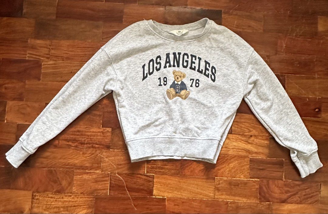 H&M Grey Los Angeles Teddy Bear Sweatshirt (Category: Coats, Jackets and Outerwear) located in Cainta. Submitted by buy.preloved (Listing ID 1464218331, Image 1). Description: - Grey H&M sweatshirt - Features 'Los Angeles 1976' graphic with a teddy bear - Crew neck, long sleeves - Cropped fit - Ideal for casual wear.