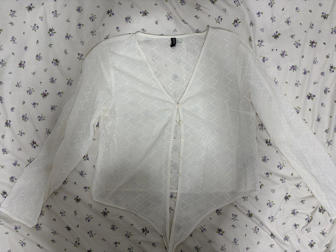 H&M White Eyelet Button-Up Long Sleeve Blouse (Category: Longsleeves) located in Calamba. Submitted by altheyanna (Listing ID 1464240855, Image 1). Description: - White eyelet blouse from H&M - Long sleeves - V-neckline - Button-up front - Textured fabric pattern - Ties at the bottom hem - Perfect for layering or wearing alone.