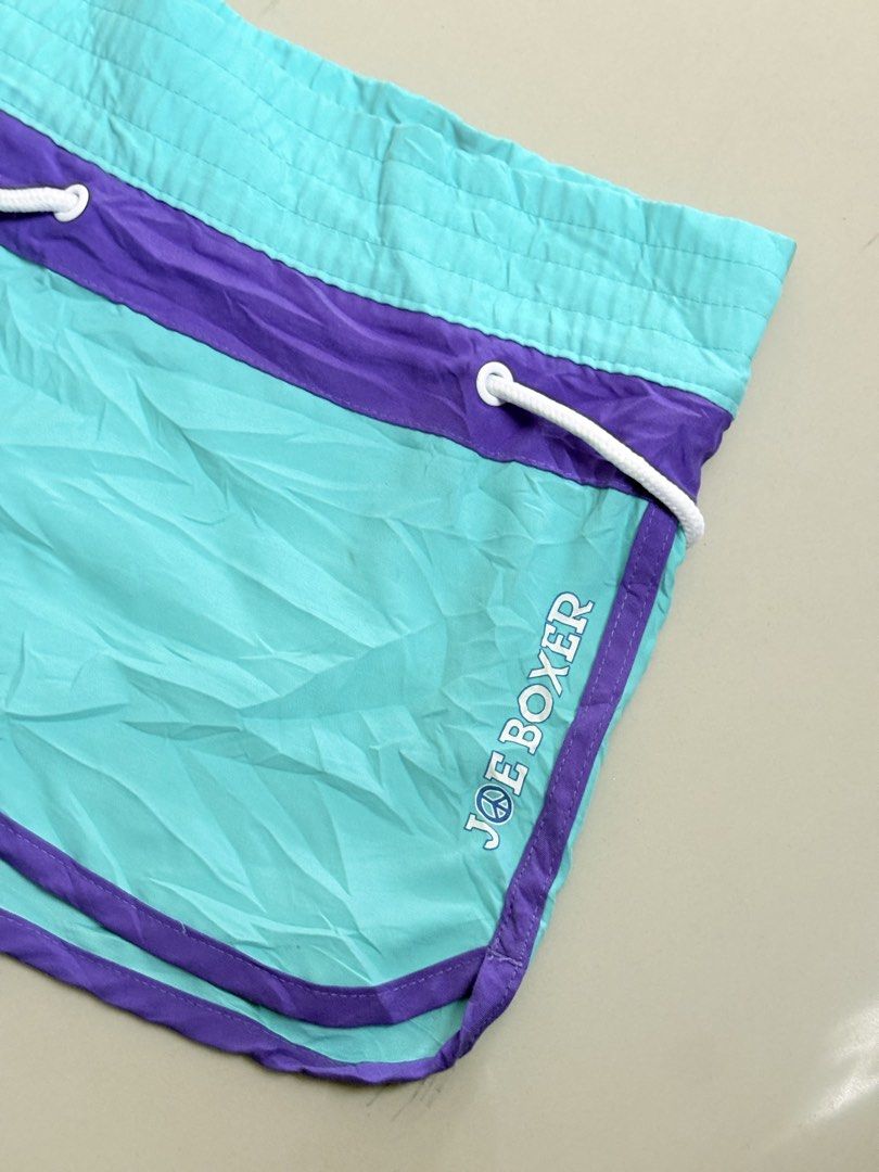 Joe boxer swim shorts (Category: Shorts) located in Binangonan. Submitted by polinn.xx (Listing ID 1464205259, Image 2). Description: Vibrant turquoise and purple Joe Boxer swim shorts feature a contrasting white drawstring and distinct side branding. Waistline: 34-36.