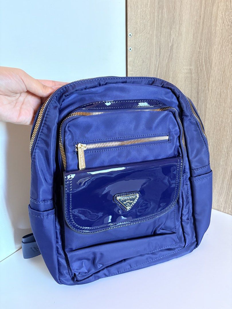 JOVANNI Navy Blue Nylon Patent Trim Backpack (Category: Backpacks) located in Taal. Submitted by aliafrncsca (Listing ID 1464163711, Image 1). Description: - Brand: JOVANNI - Color: Navy Blue - Material: Nylon with patent trim - Exterior Pockets: 1 front zip pocket, 1 flap pocket with snap button closure - Main Compartment: Zipper closure - Straps: Adjustable shoulder straps - Ideal for: Everyday use.
