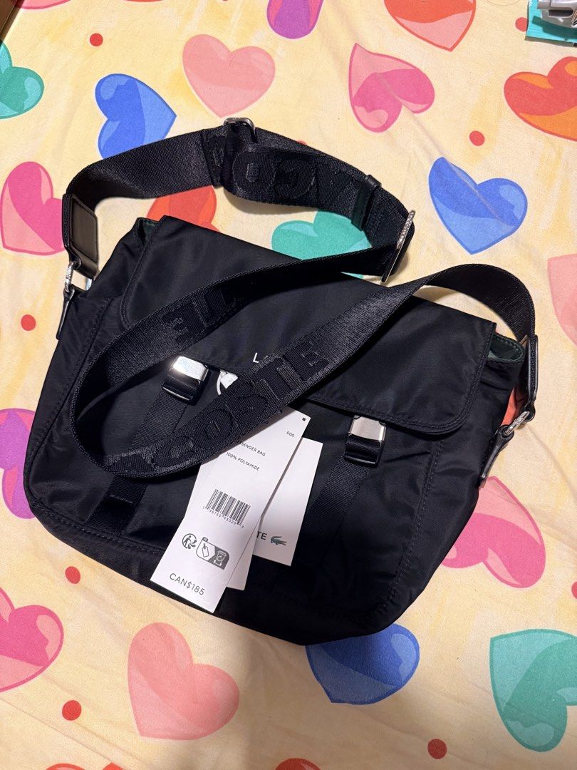Lacoste Black Nylon Messenger Bag (Category: Sling Bags) located in Pasig City. Submitted by moms_closet2024 (Listing ID 1464166985, Image 2). Description: - Authentic Black Lacoste Messenger Bag - Material: 100% Polyamide - Features: Adjustable strap with Lacoste branding, silver buckle details on front flap - Condition: Brand new with tags attached - Original Retail Price: CAN$185.