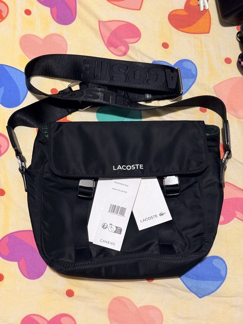 Lacoste Black Nylon Messenger Bag (Category: Sling Bags) located in Pasig City. Submitted by moms_closet2024 (Listing ID 1464166985, Image 1). Description: - Authentic Black Lacoste Messenger Bag - Material: 100% Polyamide - Features: Adjustable strap with Lacoste branding, silver buckle details on front flap - Condition: Brand new with tags attached - Original Retail Price: CAN$185.