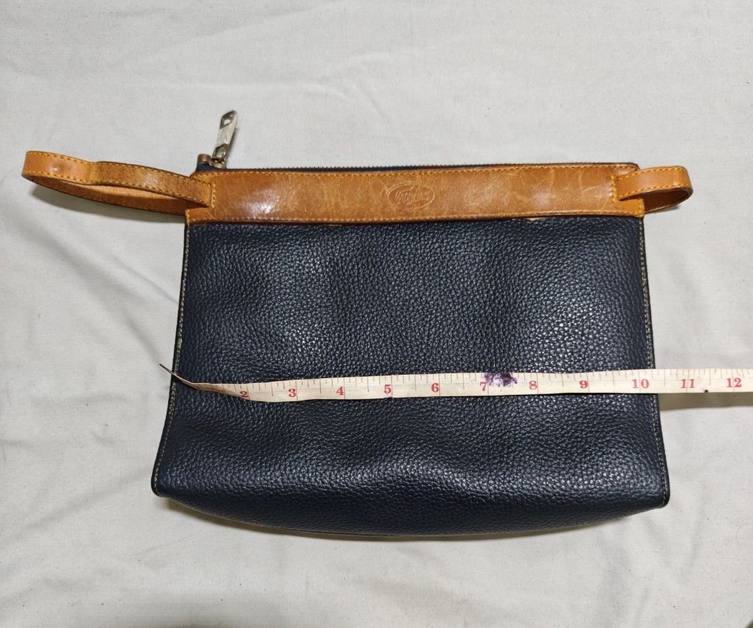 Lacoste Leather Pouch Clutch Bag (Category: Purses & Pouches) located in Isulan. Submitted by jaysthrift (Listing ID 1464225134, Image 1). Description: - Classic black and tan leather pouch by Lacoste. - Ideal size for carrying your essentials. - Secure zipper closure to keep items safe. - Interior features a small leather tag with the iconic Lacoste logo. - Convenient wrist strap attached for easy carrying. - Approximate dimensions: 9 inches wid