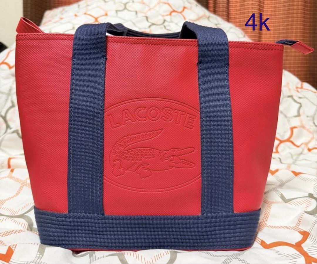 Lacoste Red and Navy Blue Tote Bag (Category: Tote Bags) located in Quezon City. Submitted by ivygolaysiz (Listing ID 1464284542, Image 1). Description: - Classic red tote bag by Lacoste. - Navy blue straps and trim for a stylish contrast. - Iconic embossed crocodile logo on the front. - Textured navy blue band on the base. - Spacious interior for all your essentials. - Ideal for everyday errands or weekend getaways..
