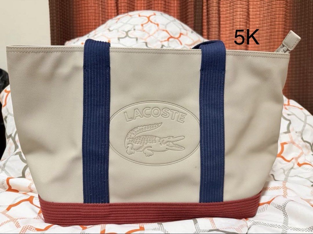 Lacoste Tote Bag Beige Navy Red (Category: Shoulder Bags) located in Quezon City. Submitted by ivygolaysiz (Listing ID 1464284997, Image 1). Description: - Classic Lacoste tote bag - Beige canvas with navy blue straps - Red trim detail at the bottom - Iconic embossed crocodile logo - Spacious and durable design - Perfect for everyday use or travel.