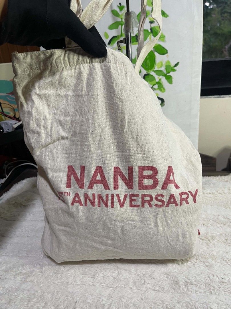 Levi's Tote Bag (Category: Tote Bags) located in Naawan. Submitted by twilly.apparel2 (Listing ID 1464217708, Image 3). Description: - Cream colored canvas tote bag - Features classic Levi's logo on one side - "NANBA 15TH ANNIVERSARY" printed in red on the other side - Drawstring closure at the top - Ideal for everyday use or as a shopping bag.