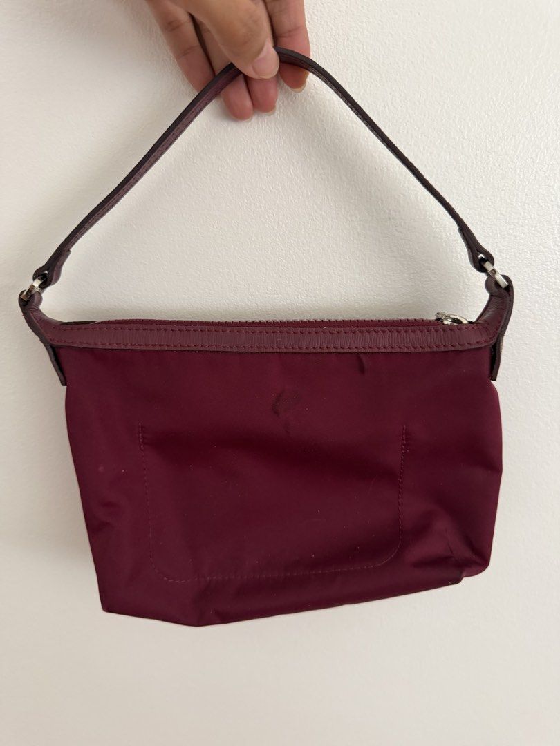 Longchamp Burgundy Nylon Pouch Bag (Category: Luxury Bags & Wallets) located in Paranaque City. Submitted by ferrewr (Listing ID 1464195512, Image 2). Description: - Burgundy Longchamp nylon pouch - Features leather trim and strap - Secure zipper closure - Interior pocket for small items - Minor marks on exterior fabric - Ideal for bag organization or as a standalone clutch.