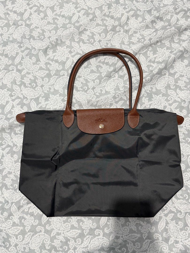 Longchamp Le Pliage Tote Bag Dark Grey (Category: Luxury Bags & Wallets) located in Quezon City. Submitted by akestrella (Listing ID 1464278622, Image 1). Description: - Classic Longchamp tote bag - Color: Dark grey nylon with brown leather handles and trim - Closure: Zip top main compartment - Ideal for: Everyday use, travel, or as a spacious carry-all - Approximate Dimensions: 17 inches (width) x 12 inches (height).