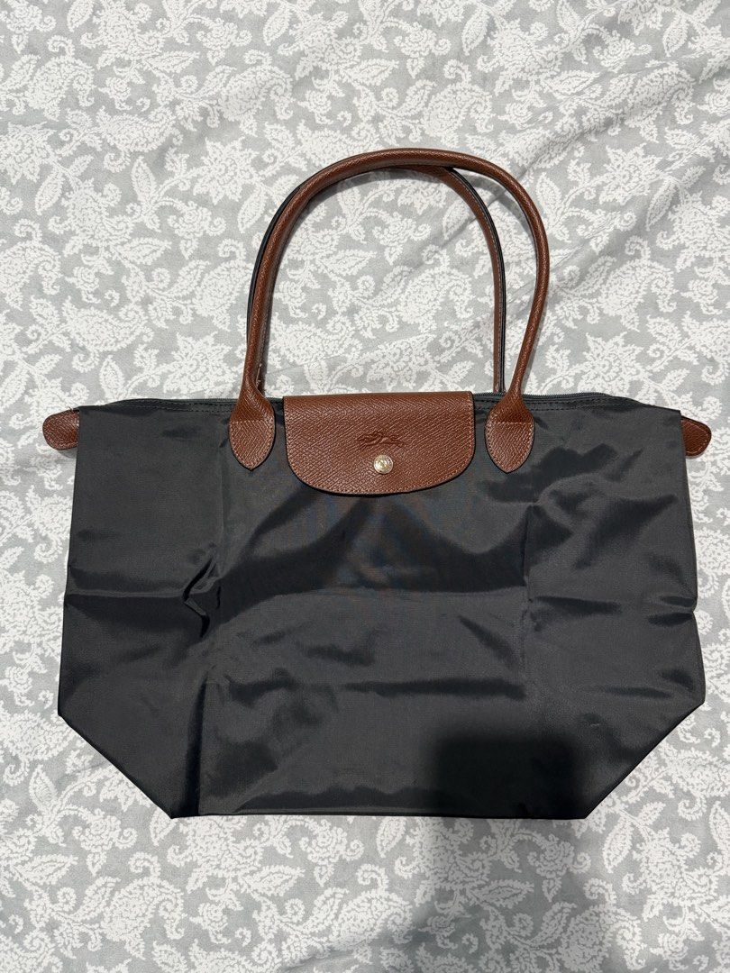 Longchamp Le Pliage Tote Bag Dark Grey (Category: Luxury Bags & Wallets) located in Quezon City. Submitted by akestrella (Listing ID 1464278622, Image 2). Description: - Classic Longchamp tote bag - Color: Dark grey nylon with brown leather handles and trim - Closure: Zip top main compartment - Ideal for: Everyday use, travel, or as a spacious carry-all - Approximate Dimensions: 17 inches (width) x 12 inches (height).
