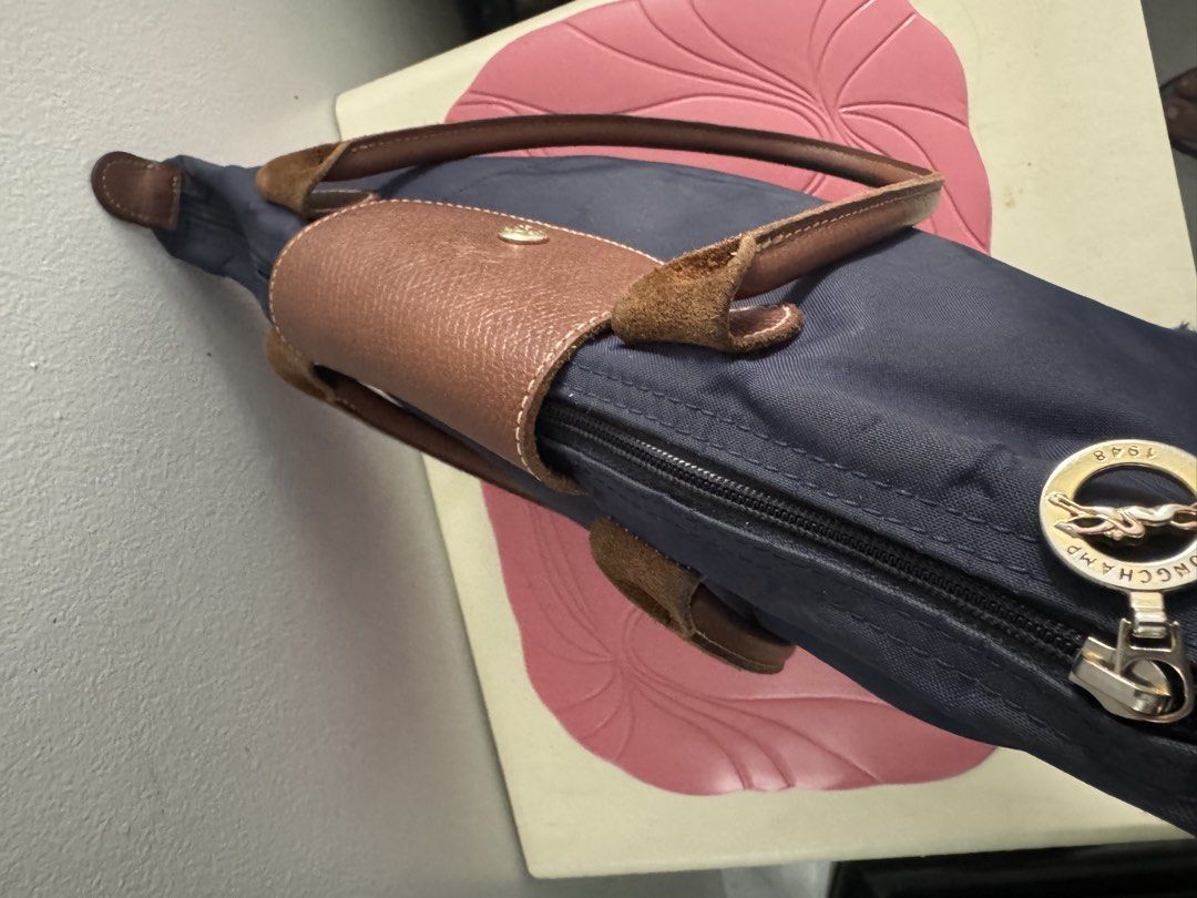 Longchamp Le Pliage Tote Bag Navy Blue (Category: Luxury Bags & Wallets) located in Manila. Submitted by decluterthings888 (Listing ID 1464337500, Image 1). Description: - Classic Longchamp Le Pliage tote bag - Color: Navy blue nylon with brown leather handles and trim - Closure: Zipper with snap button flap - Features: Interior pocket - Practicality: Folds flat for easy storage - Style: Timeless and perfect for everyday use.