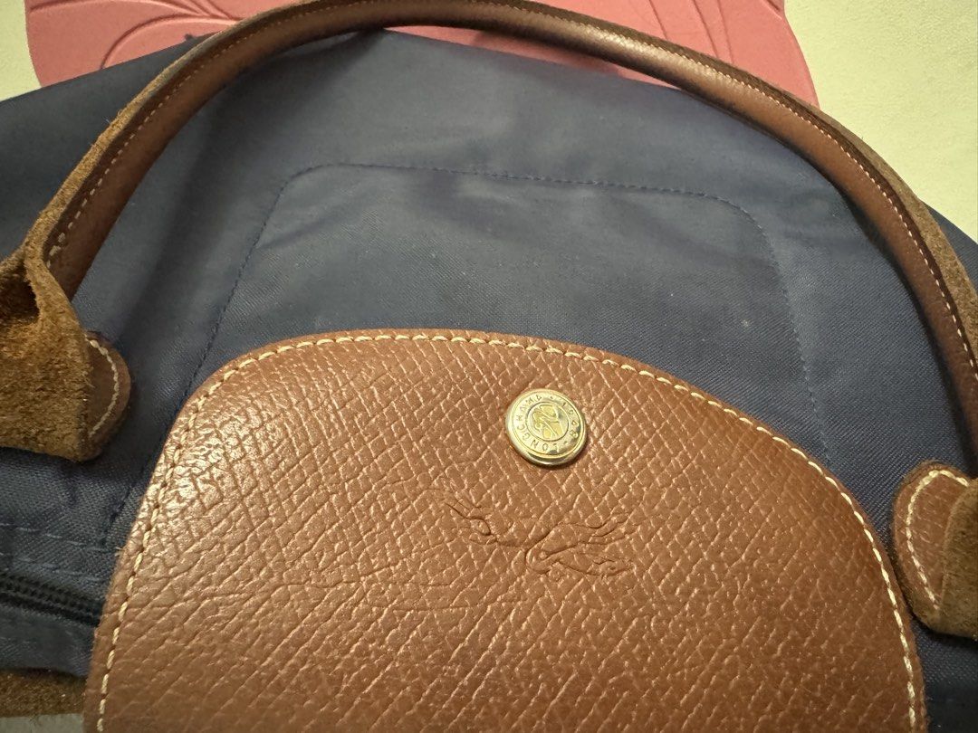 Longchamp Le Pliage Tote Bag Navy Blue (Category: Luxury Bags & Wallets) located in Manila. Submitted by decluterthings888 (Listing ID 1464337500, Image 3). Description: - Classic Longchamp Le Pliage tote bag - Color: Navy blue nylon with brown leather handles and trim - Closure: Zipper with snap button flap - Features: Interior pocket - Practicality: Folds flat for easy storage - Style: Timeless and perfect for everyday use.