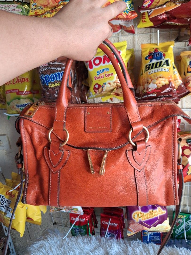 Marc Jacobs Leather Satchel Handbag (Category: Cross-body Bags) located in Agoncillo. Submitted by vinsoy07 (Listing ID 1464141061, Image 3). Description: - Authentic Marc Jacobs orange leather satchel bag - Elegant gold hardware details - Versatile with top handles and a detachable shoulder strap - Organized interior with multiple pockets - Crafted in Italy - Ideal for everyday wear.
