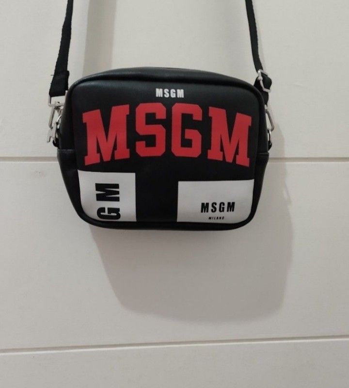 MSGM Milano Black Red Logo Crossbody Bag (Category: Cross-body Bags) located in Mabalacat. Submitted by uniqlover (Listing ID 1464272906, Image 3). Description: - Stylish black crossbody bag - Features a bold red MSG M logo - Small MSG M Milano tag on the side - Secure zipper closure - Elegant silver hardware with a cute 'M' charm - Adjustable strap for comfortable wear - Ideal for everyday use.