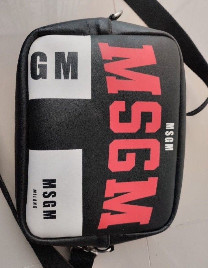 MSGM Milano Black Red Logo Crossbody Bag (Category: Cross-body Bags) located in Mabalacat. Submitted by uniqlover (Listing ID 1464272906, Image 2). Description: - Stylish black crossbody bag - Features a bold red MSG M logo - Small MSG M Milano tag on the side - Secure zipper closure - Elegant silver hardware with a cute 'M' charm - Adjustable strap for comfortable wear - Ideal for everyday use.