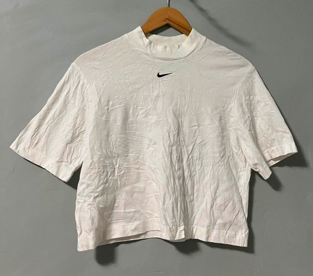 Nike White Mock Neck Cropped T-shirt (Category: Shirts) located in Compostela. Submitted by zackthrift07 (Listing ID 1464307199, Image 1). Description: - White Nike cropped t-shirt - Mock neck style - Small embroidered Nike swoosh logo on chest - Short sleeves - Tag indicates size S - Ideal for casual wear.
