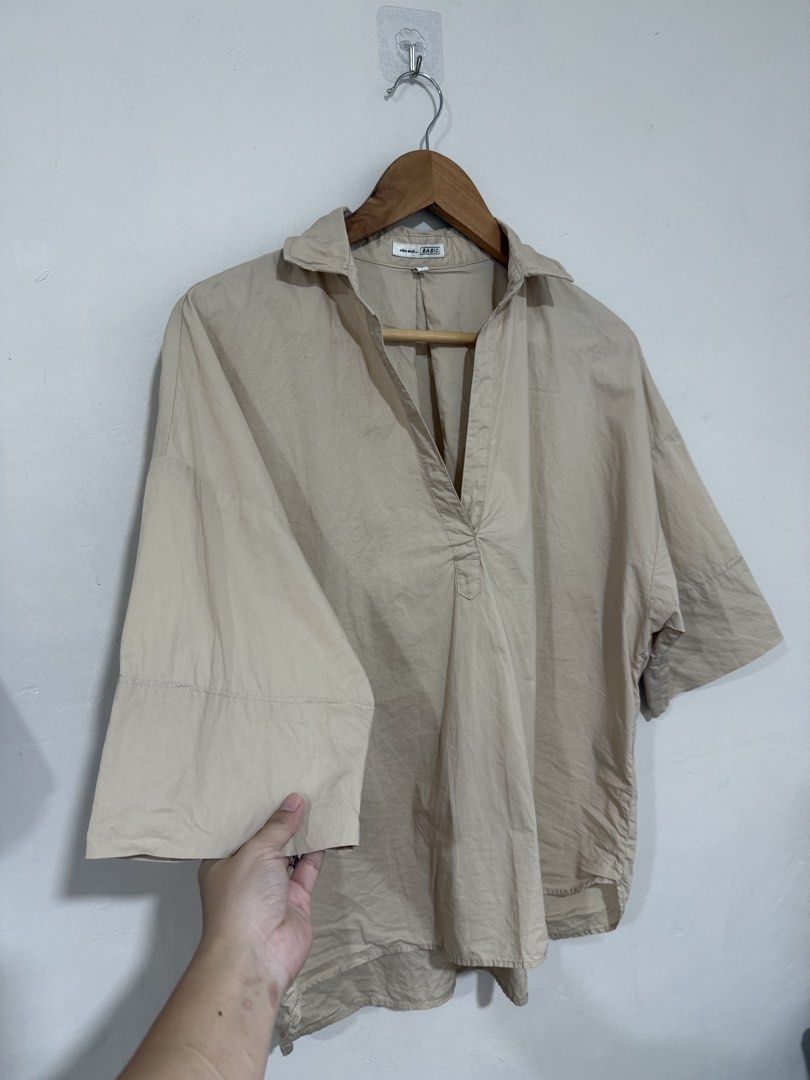 Niko And… Beige Office Top (Category: Others Tops) located in Manila. Submitted by morningthrifters (Listing ID 1464219712, Image 3). Description: niko and... beige oversized skipper shirt. It features a relaxed silhouette with wide half-sleeves and an open, buttonless v-neckline typical of classic Japanese utility and city-casual styles. Similar variations of this shirt often feature a subtly wired structured collar or a comfortable cotton-linen