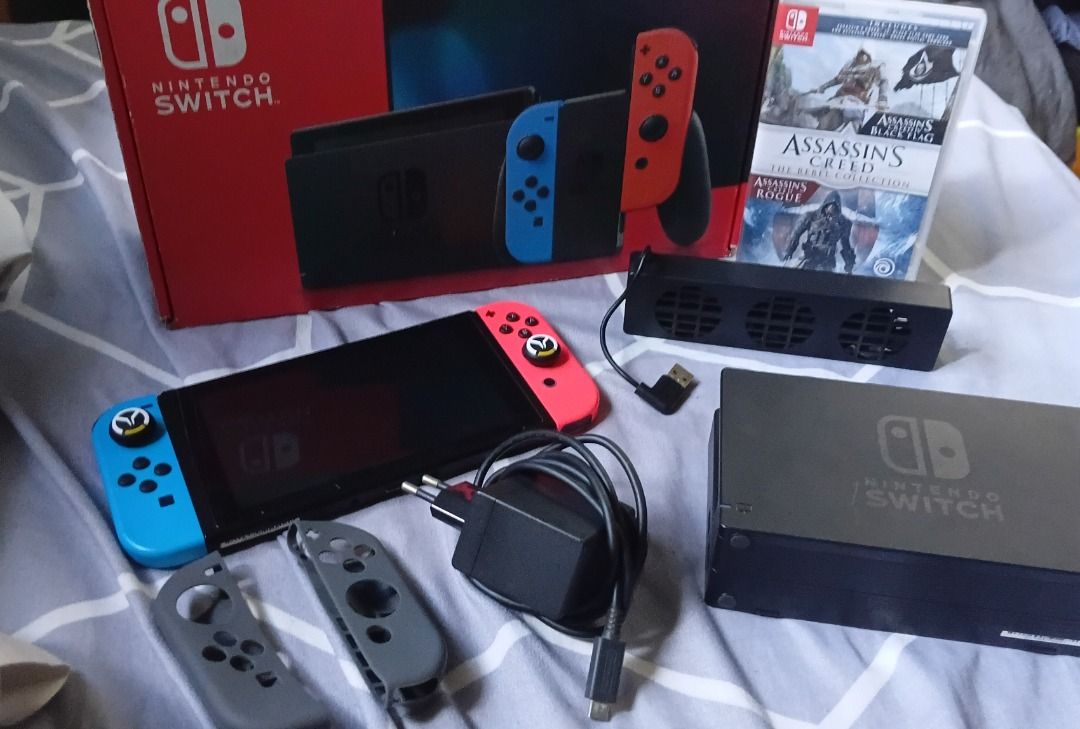 Nintendo Switch Console with Games and complete Accessories (Category: Nintendo) located in Caloocan City. Submitted by wifiskelly (Listing ID 1464214128, Image 1). Description: - Nintendo Switch Console - Original Box Included - Official Dock - Blue and Red Joy-Cons - AC Adapter - Assassin's Creed Game Cartridge - Cooling Fan Attachment - Screen displays game library and The Legend of Zelda: Breath of the Wild - Ideal for both home and on-the-go