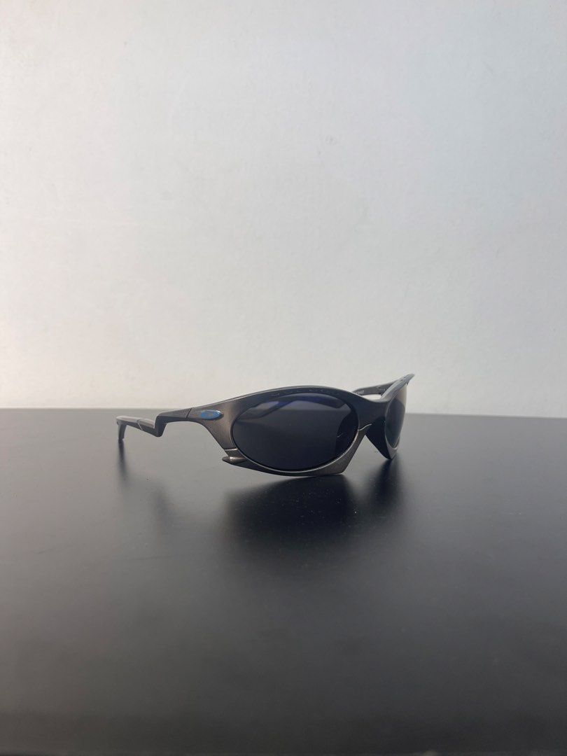 Oakley Plantaris (Category: Sunglasses & Eyewear) located in Manila. Submitted by mine2ownit (Listing ID 1464227612, Image 2). Description: - Dark lenses with a subtle blue tint - Dark grey frame with distinctive zig-zag arm design - Classic Oakley model - Excellent for sports and everyday wear - Provides good coverage and a secure, comfortable fit.