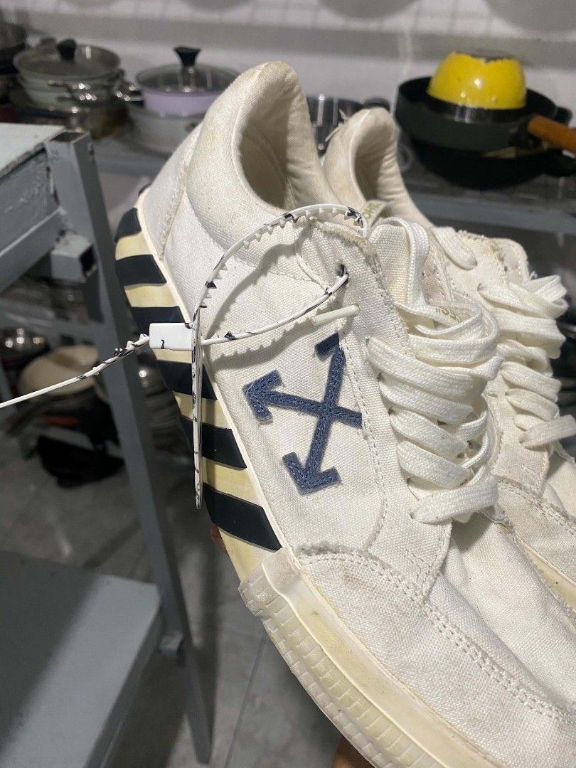 Off-White Low Top Canvas Sneakers Size 44 (Category: Sneakers) located in Bacolod City. Submitted by rimboythrift (Listing ID 1464194588, Image 2). Description: - Brand: Off-White - Type: White Canvas Low Top Sneakers - Size: 44 - Features: Iconic arrow logo on side, diagonal stripes on heel, Off-White logo on insole - Origin: Made in Indonesia - Condition: Shows some signs of wear on sole and canvas - NEED WASH .