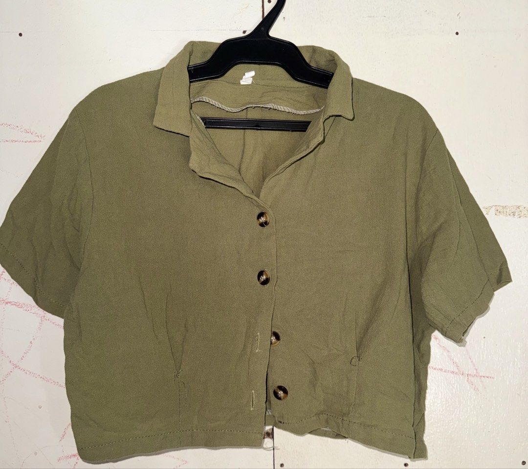 Olive Green Cropped Button-Up Shirt (Category: Shirts) located in Santiago. Submitted by eogg30 (Listing ID 1464140274, Image 1). Description: - Olive green cropped shirt - Collared neckline - Short sleeves - Button-up closure - Two front pockets - Slightly crinkled fabric texture - Ideal for pairing with high-waisted bottoms.