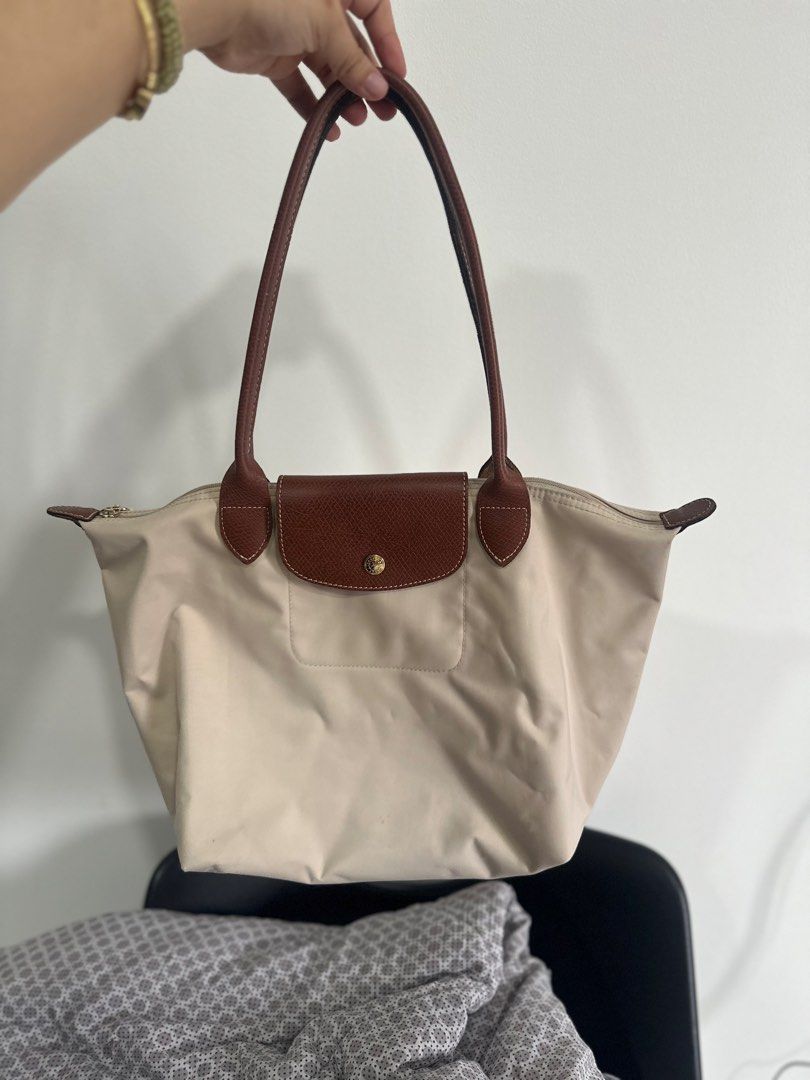 Original Longchamp Le Pliage Tote Bag Beige (Category: Luxury Bags & Wallets) located in Cavite. Submitted by prelovedbymaeve (Listing ID 1464198708, Image 1). Description: - Classic Longchamp tote bag - Beige nylon with brown leather handles and trim - Secure zipper closure with snap button flap - Ideal for everyday use - Spacious interior.