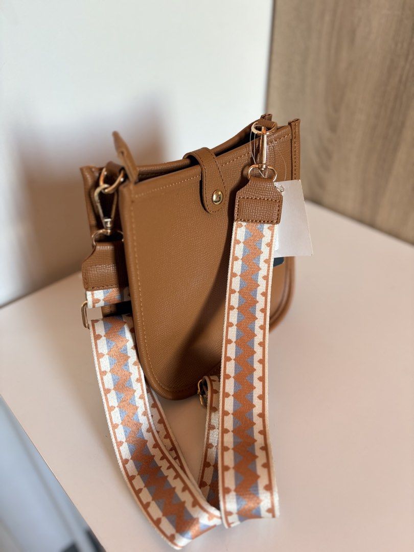 PARISIAN Tan Crossbody Bag with Patterned Strap (Category: Cross-body Bags) located in Taal. Submitted by aliafrncsca (Listing ID 1464162718, Image 2). Description: - Parisian tan crossbody bag - Detachable patterned strap included - Main compartment with interior zip pocket - Magnetic snap closure on front flap - Elegant gold hardware details - Ideal for everyday wear.