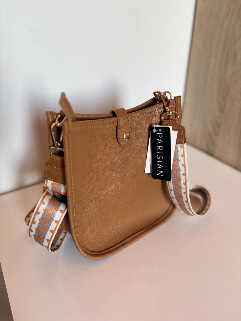 PARISIAN Tan Crossbody Bag with Patterned Strap (Category: Cross-body Bags) located in Taal. Submitted by aliafrncsca (Listing ID 1464162718, Image 1). Description: - Parisian tan crossbody bag - Detachable patterned strap included - Main compartment with interior zip pocket - Magnetic snap closure on front flap - Elegant gold hardware details - Ideal for everyday wear.