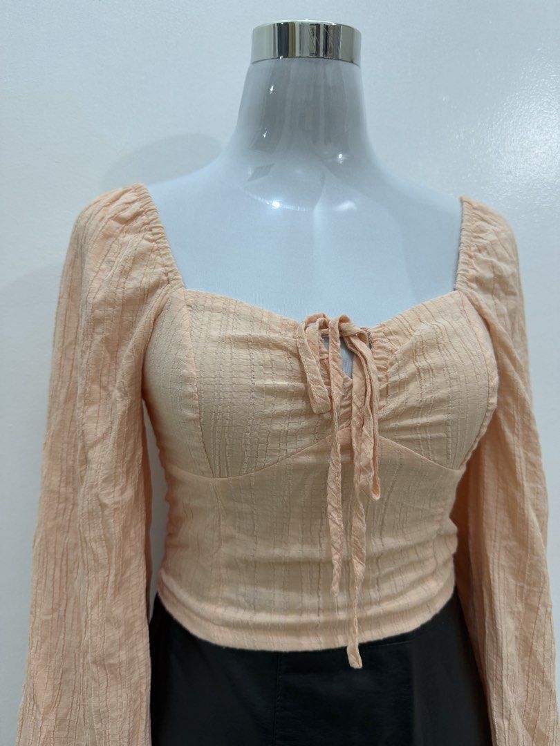 Peach Square Neck Tie Front Long Sleeve Top (Category: Longsleeves) located in Manila. Submitted by e.louise (Listing ID 1464334559, Image 3). Description: - Adorable peach top - Flattering square neckline - Chic tie-front detail - Stylish long puff sleeves - Textured fabric for added appeal - Versatile: pairs well with skirts or jeans - A must-have addition to your wardrobe.