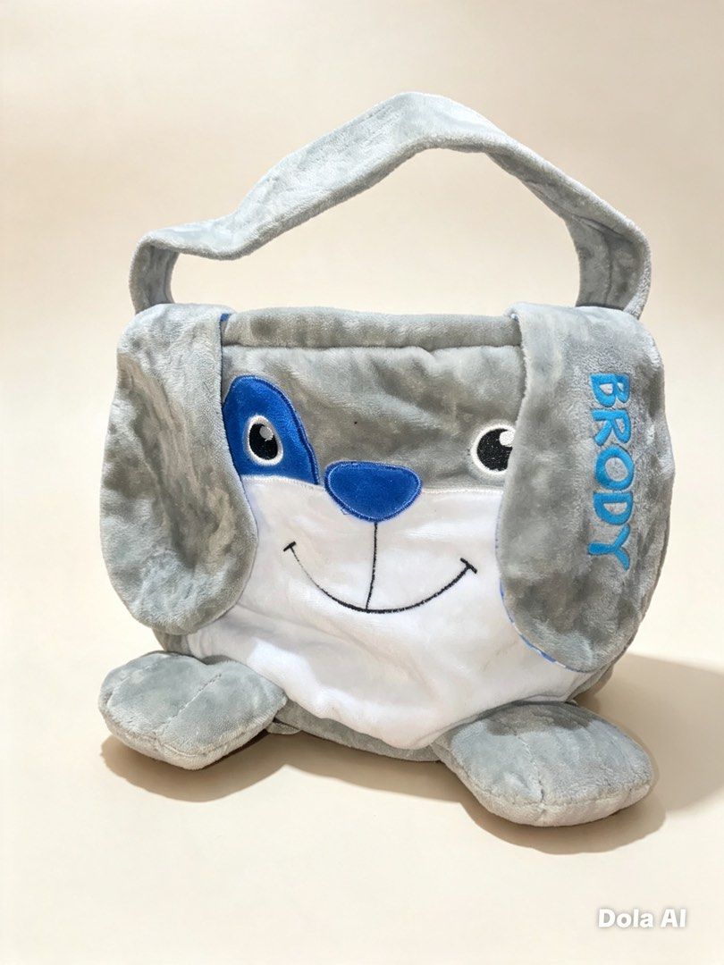 Personalized Plush Dog Bag "BRODY" (Category: Tote Bags) located in Manila. Submitted by reginemarquez412 (Listing ID 1464233602, Image 1). Description: - Adorable plush bag shaped like a gray dog. - "BRODY" embroidered on the side in blue. - Blue accents on the dog's face. - Comes with a convenient carrying handle. - Ideal for kids to store toys, snacks, or small essentials..
