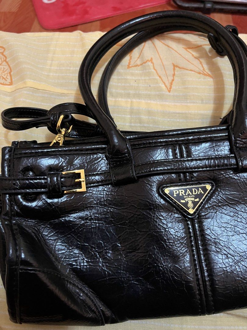 Prada Black Leather Handbag with Shoulder Strap (Category: Luxury Bags & Wallets) located in Quezon City. Submitted by reluxefinds2025 (Listing ID 1464179106, Image 2). Description: - Authentic Prada handbag, Made in Italy - Features elegant top handles - Includes a detachable shoulder strap for versatility - Accented with luxurious gold hardware - Interior zippered pocket for secure storage - Lined with signature Prada logo fabric - Ample space 