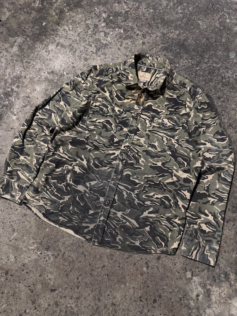 Roebuck & Co. Camouflage Button-Up Shirt (Category: Tshirts & Polo Shirts ) located in Pasig City. Submitted by dripthrift1600 (Listing ID 1464247420, Image 1). Description: - Brand: Rocawear & Co. - Style: Camouflage button-up shirt - Sleeves: Long sleeves with button cuffs - Pockets: Two chest pockets with button closures - Closure: Button-down front - Occasion: Great for casual wear - Condition: Please check photos for details - Dimes: 23x28.